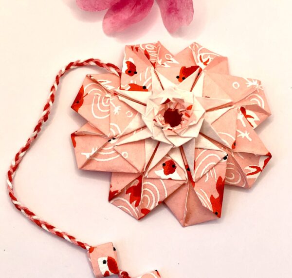 Marque page en origami , en forme de mandala et de couleur rose et rouge
